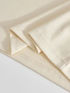Detailansicht der hochwertigen Nähte und Twill-Stoffstruktur eines beigen Herren-Poloshirts.
