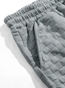 Dettaglio macro di pantaloncini grigi in maglia waffle con elastico in vita e tasca.
