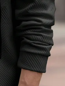 Gros plan détaillé sur la texture du tissu jacquard épais sur la manche de la veste homme.