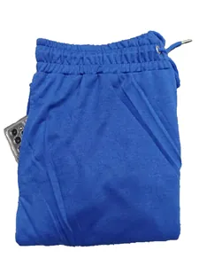 Dettaglio dei pantaloni sportivi blu con tasca laterale che contiene uno smartphone.