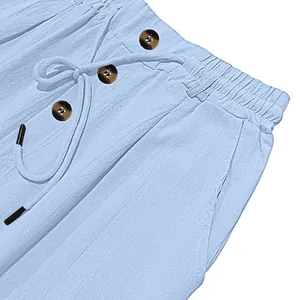 Close-up of light blue cotton linen trousers with drawstring and button details