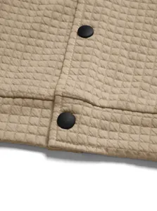 Macro detail of khaki waffle knit jacket fabric showing black buttons and fine texture