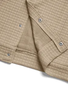 Detailed close-up of a khaki quilted jacket featuring waffle texture and silver snap buttons