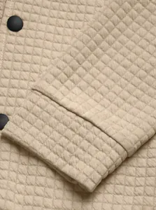 Detailed macro view of beige waffle knit fabric texture and cuff on a men's casual jacket
