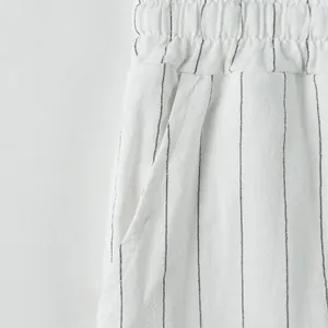 Close-up detail of white striped linen pants showing waistband and pocket texture
