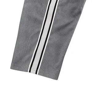 Nahaufnahme einer grauen Cordhose mit sportlichen schwarz-weißen Seitenstreifen.