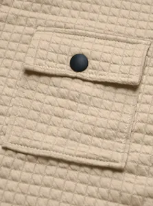 Macro detail of a functional pocket with button on a waffle knit men's casual jacket