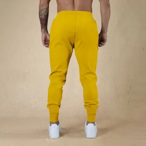 Vista posteriore dei pantaloni sportivi gialli da uomo con polsini a coste elasticizzati.