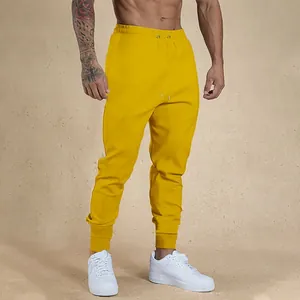 Men's yellow fitness joggers with tapered cuffs and drawstring waist for gym workouts.