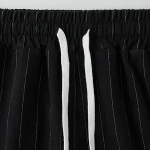 Close-up detail of the elastic waistband with white drawstring on black pinstripe linen trousers.