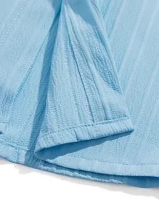 Dettaglio del tessuto strutturato azzurro con cuciture accurate per camicia estiva da uomo.