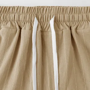 Close-up detail of linen summer pants featuring elastic waist and white drawstring.