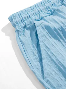 Dettaglio dei pantaloncini testurizzati azzurri con vita elastica e tasca laterale