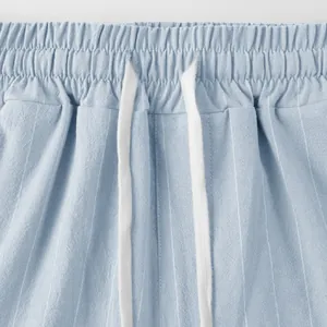 Detail of blue striped linen pants featuring elastic waistband and white drawstring