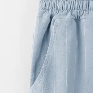 Detailed macro view of light blue striped linen trousers waistband and side pocket