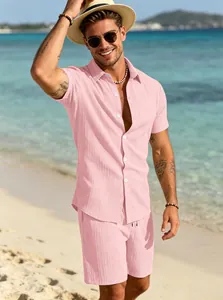 Primo piano di un set estivo da uomo con camicia e pantaloncini rosa sulla spiaggia.