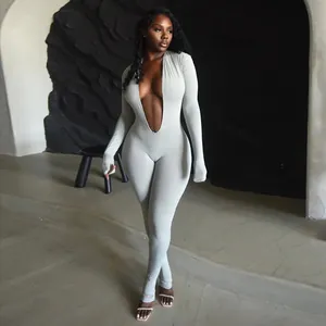 Model wearing a sexy grey deep V-neck long sleeve tight jumpsuit in a modern studio