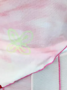 Gros plan sur un tissu en maille tie-dye rose avec imprimé fleur verte et coutures overlock