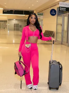 Modella che posa in un vivace set casual a tre pezzi rosa acceso in un terminal dell'aeroporto