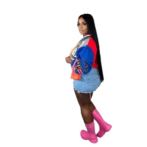 Mujer con sudadera de retazos coloridos con letras y shorts de mezclilla en una pose lateral