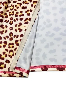 Macro detail of leopard print fabric with white zipper and red stitching accents