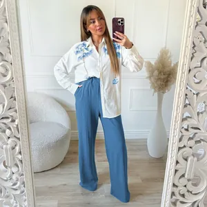 Stylish women's two-piece outfit featuring a white floral embroidered shirt and blue pants