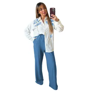 Detailed view of women's two-piece set featuring embroidered shirt and blue pants