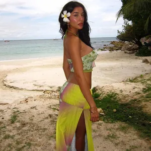 Modelo con top corto estampado y falda larga con abertura en una playa soleada