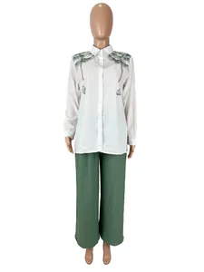 Stylish two-piece women's set with a palm tree print white shirt and green trousers
