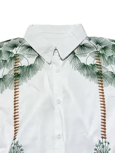 Close-up of a white button-down shirt featuring tropical green palm tree prints