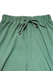 Close-up of women's casual pants showing green textured fabric and drawstring waistband