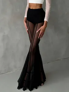 Detailed close-up of sexy black mesh flared trousers with sheer panels and slim fit design.
