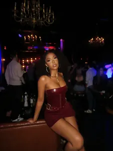 Detail of sexy wine red leather corset top and bodycon mini skirt set in nightclub.