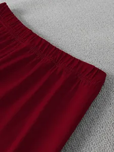 Gros plan détaillé sur la taille élastique et la texture douce en velours bordeaux du pantalon.