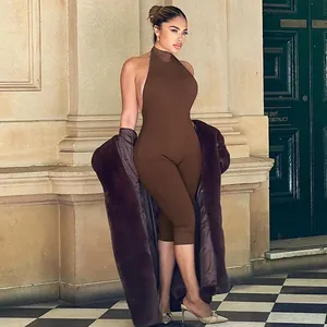 Woman in a brown backless jumpsuit and faux fur coat standing in front of a green door