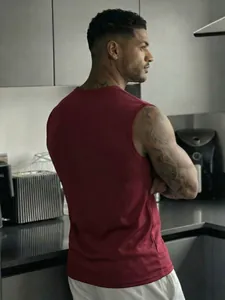 Back view of a men's maroon sports tank top showing athletic fit in a kitchen setting