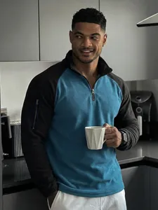 Hombre con sudadera de forro polar bicolor azul y negro en un ambiente de cocina