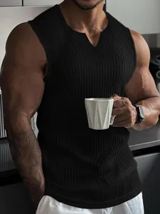 Muskulöser Mann trägt ein schwarzes, geripptes V-Ausschnitt Fitness-Tanktop in der Hand