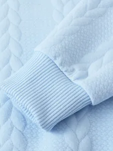 Dettaglio ravvicinato di un maglione lavorato a maglia azzurro con polsini a coste