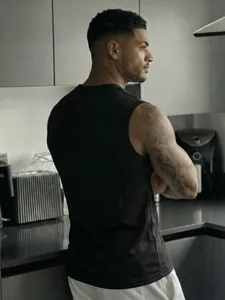 Detailed view of black mesh sports tank top showing breathable fabric on a male model
