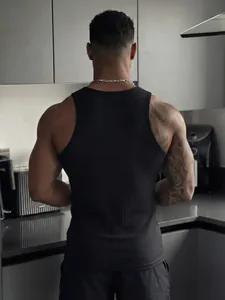 Detailed back view of a men's black ribbed fitness tank top in a modern kitchen