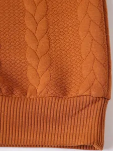 Primo piano della trama di un maglione a trecce arancione con motivi jacquard dettagliati
