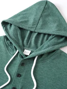Close-up of green men's henley hoodie showing fabric texture and care label detail.