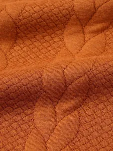 Primo piano di un maglione arancione lavorato a maglia con trama jacquard a foglie dettagliata