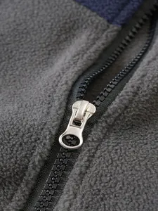 Primer plano de una cremallera metálica en una sudadera de forro polar gris para hombre