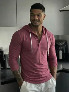Model wearing a maroon long-sleeved Henley hoodie with white drawstrings in a modern kitchen.