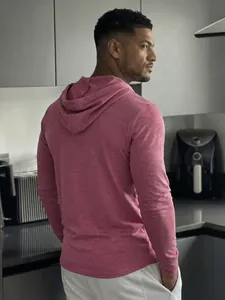 Rear view of a man wearing a casual pink long-sleeve hoodie in a modern kitchen