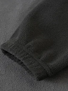 Vista detallada que muestra la textura suave del puño de una sudadera de forro polar negro.