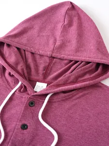 Detailed macro view of a maroon men's hoodie collar featuring buttons and white drawstrings