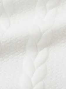 Dettaglio macro del tessuto del maglione a trecce bianco con texture morbida